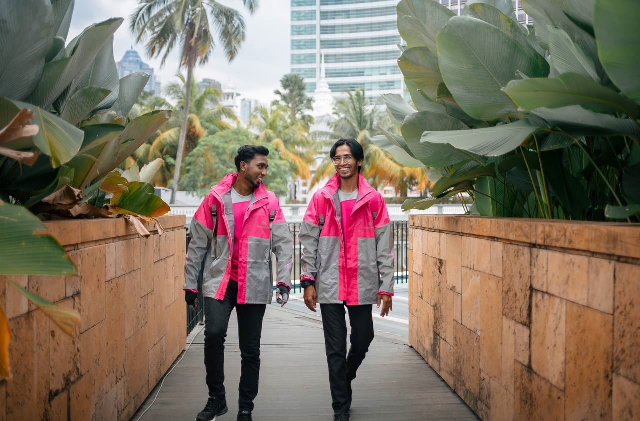 2 foodpanda riders in uniform laughing with each other