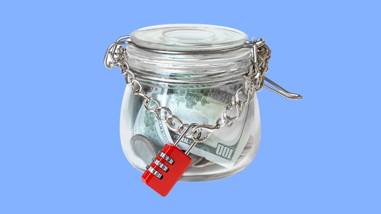 a glass jar filled with money in chain and lock