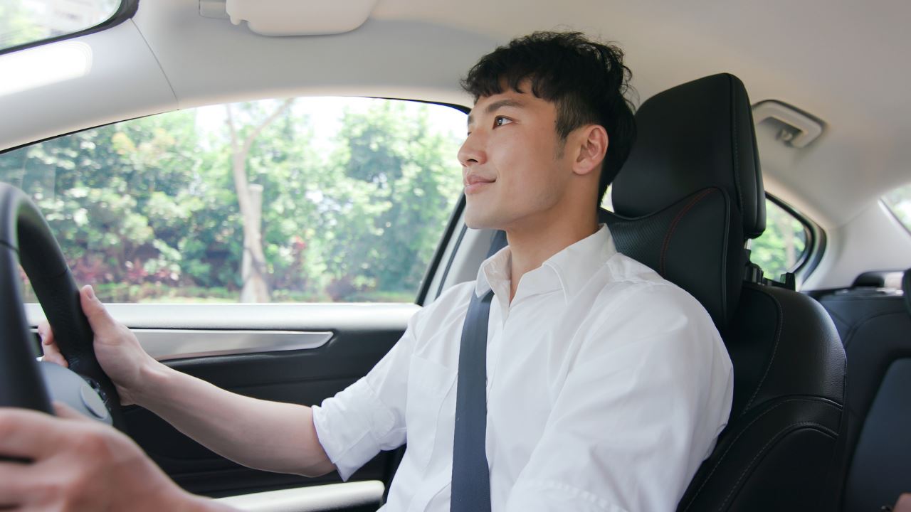 Young asian man driving his car on a sunny day