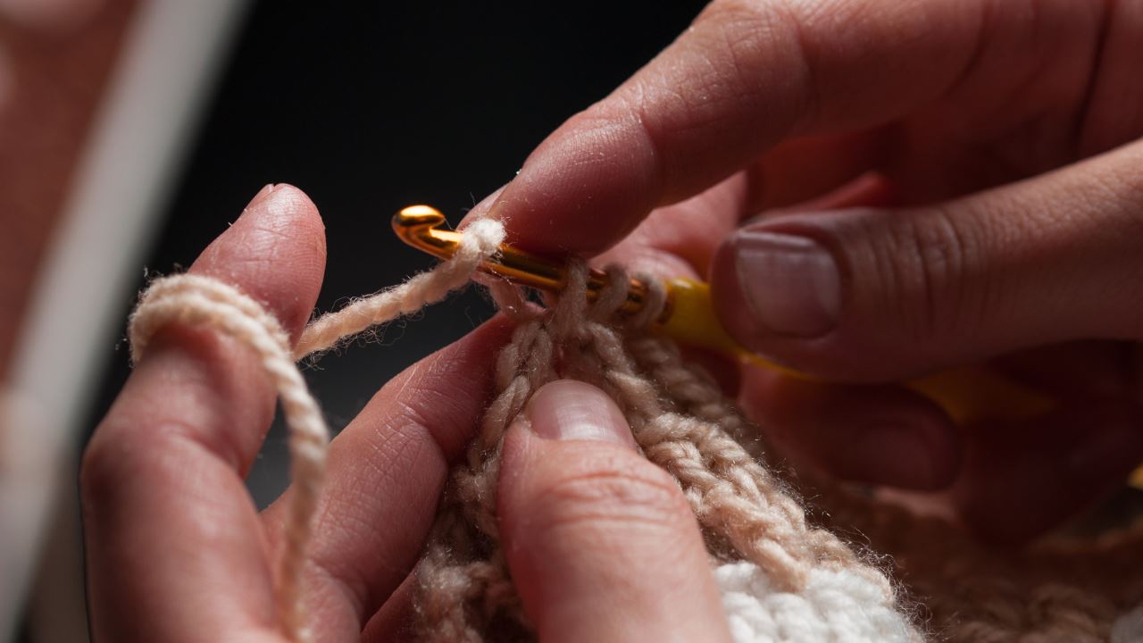 A close-up shot of a pair of hands crocheting