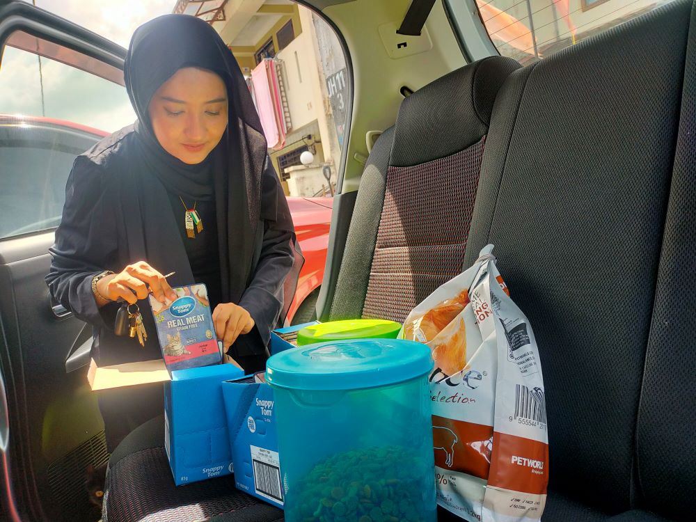 A girl holding pet food inside her car